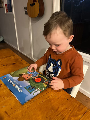 Young boy reading George the Farmer Haystack Hat-trick picture storybook